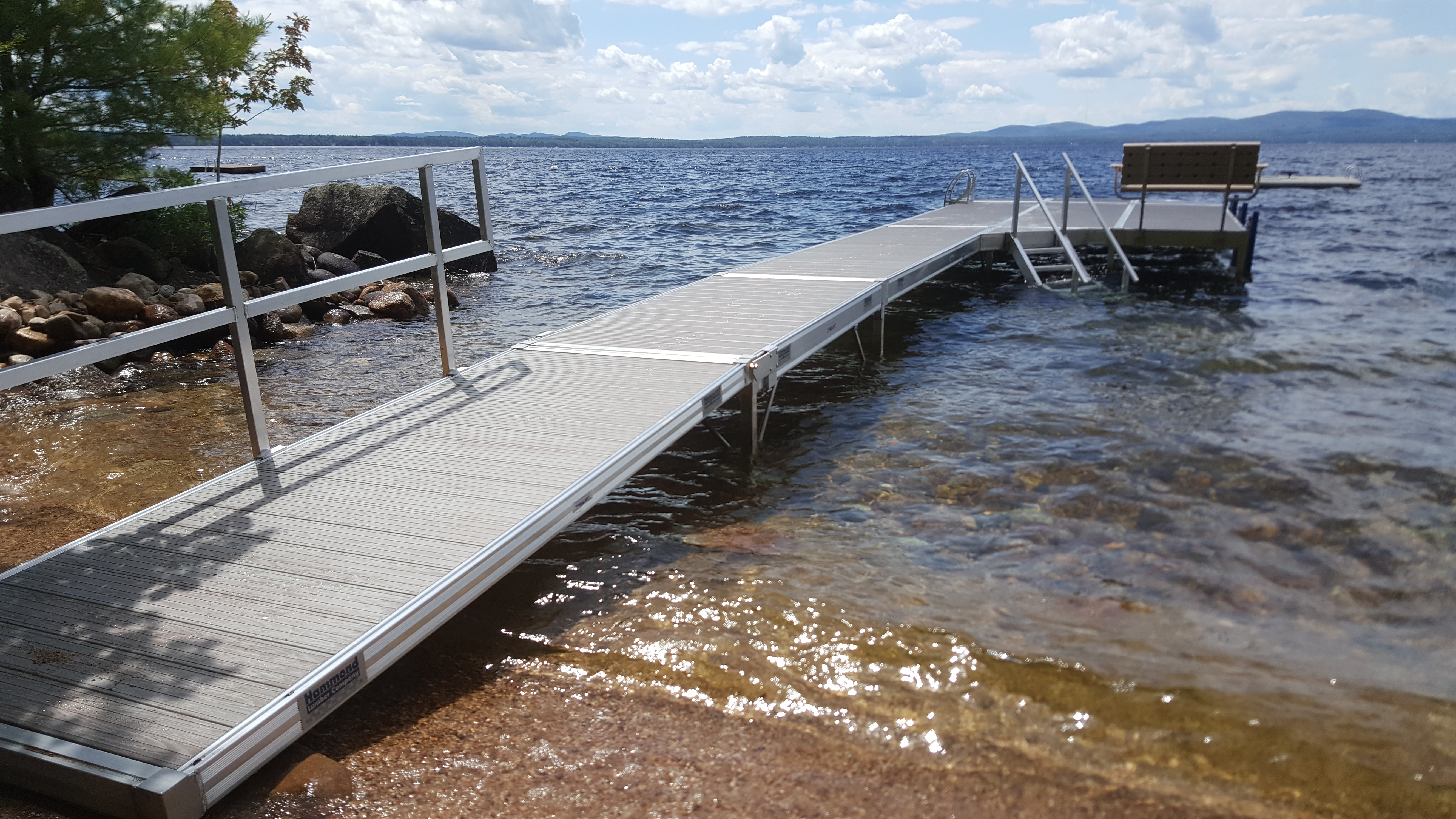 An aluminum dock system with handrails and a bench extending into a lake.