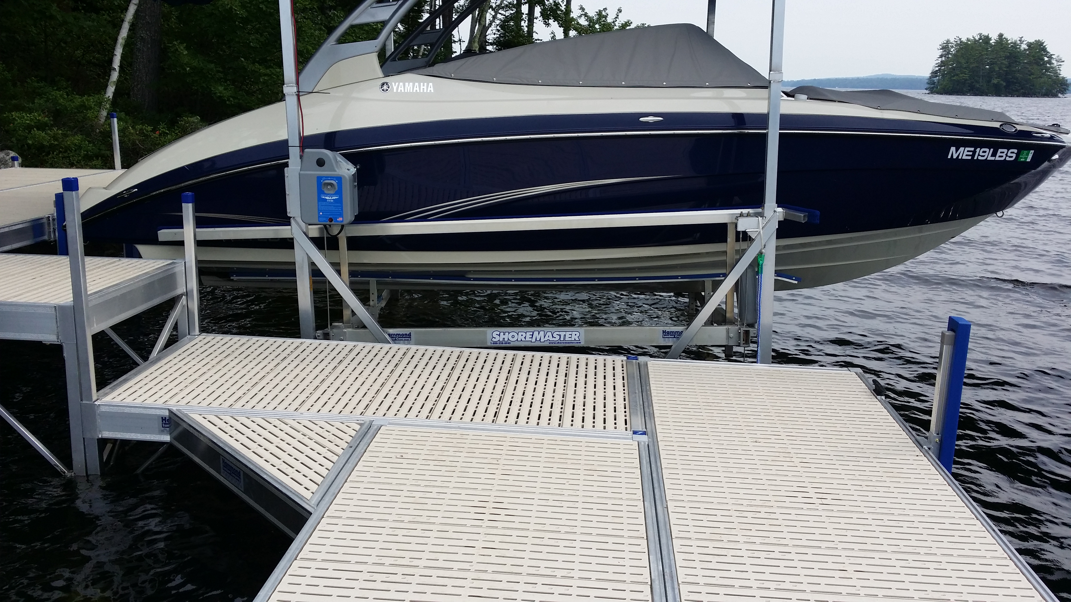 Yamaha boat raised on a ShoreMaster boat lift beside a modular dock on the lake.