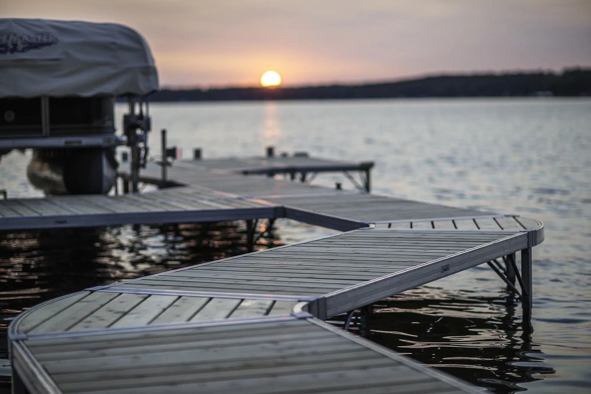 Covered ShoreMaster boat lift beside an aluminum dock