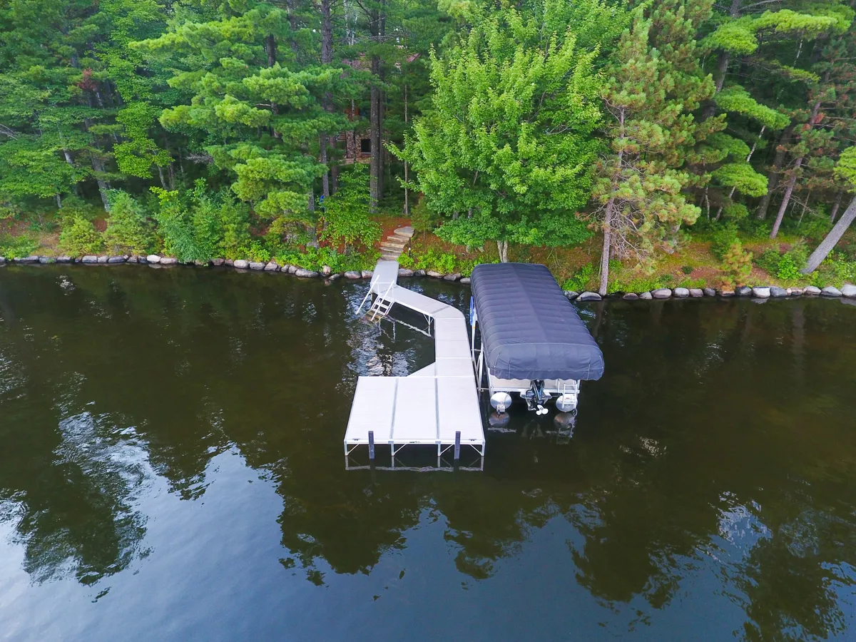 Aerial view of a boat lift with a black canopy on a dock extending into a lake